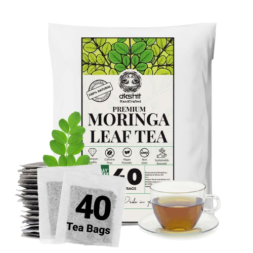 A white stand-up pouch of Akshit Premium Moringa Leaf Tea with a green leaf graphic on the label, shown alongside a stack of individual tea bags, a green moringa leaf sprig, and a glass cup of brewed tea on a white background.